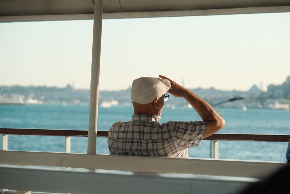 A senior man enjoys a relaxing ferry ride overlooking a serene sea view.
