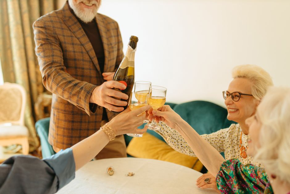 Seniors enjoying a festive gathering, toasting with wine glasses in a warm indoor setting.