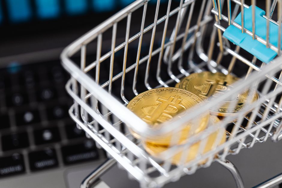 Close-up of bitcoins in a shopping cart placed on a laptop, symbolizing digital currency trading.