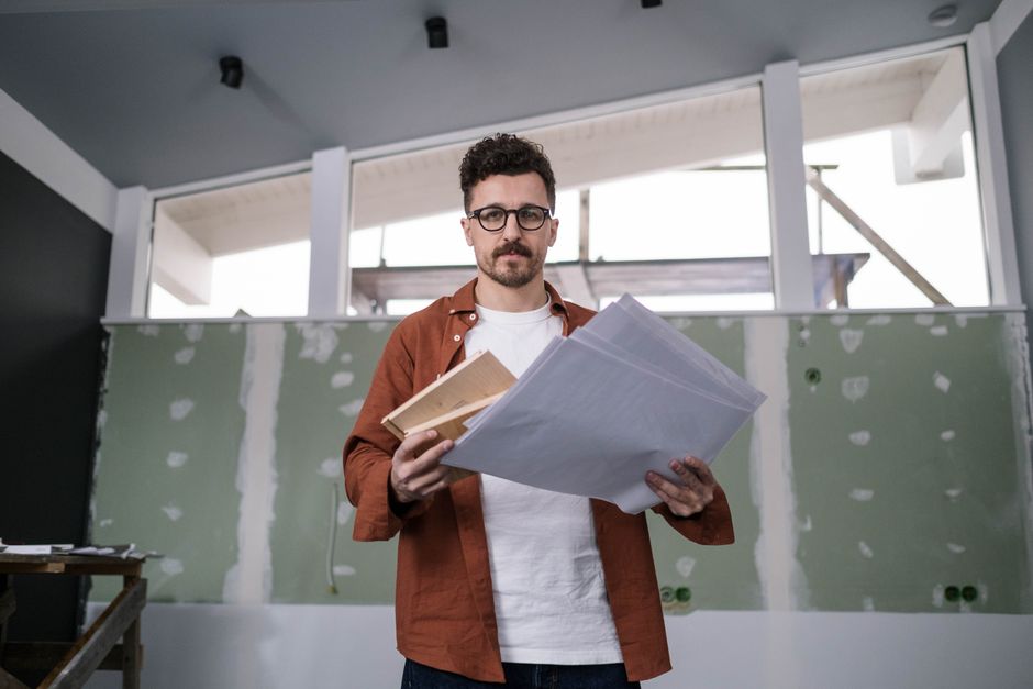 Architect holding and reviewing design documents in a modern interior setting.