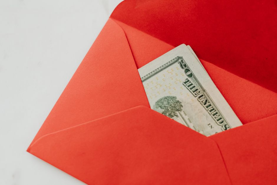 A red envelope containing U.S. dollar bills, symbolizing wealth and gifting.