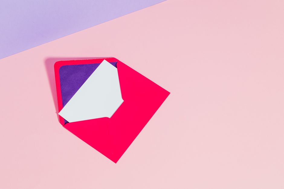 Bright red envelope with white card on a pastel pink and purple background