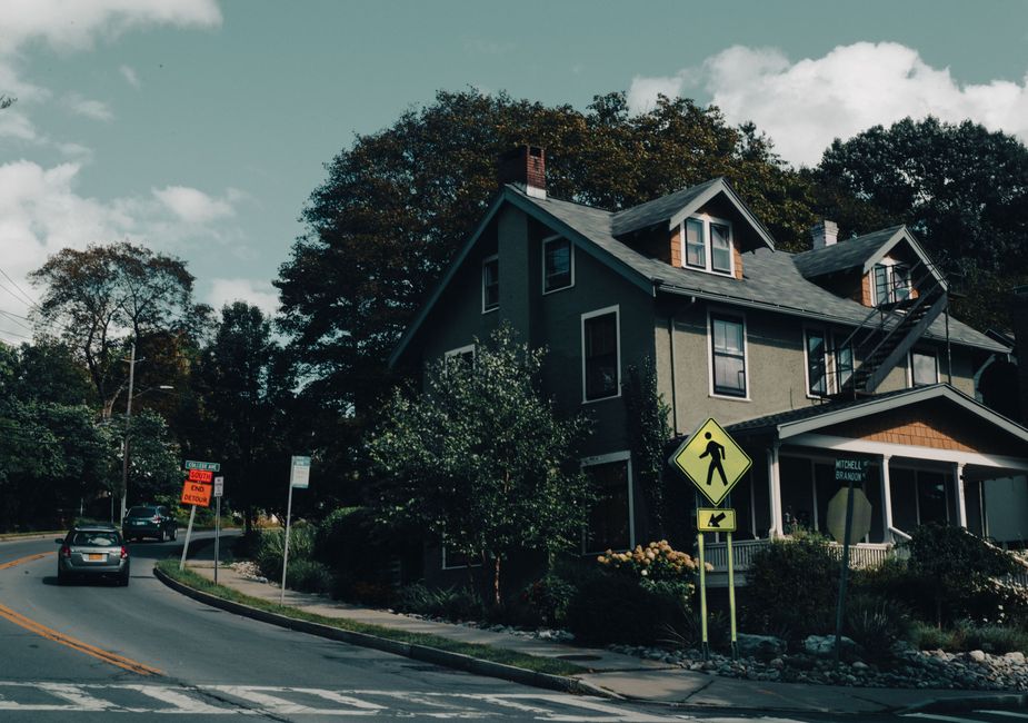 A picturesque suburban house on a quiet street next to a pedestrian crossing, captured in soft daylight.