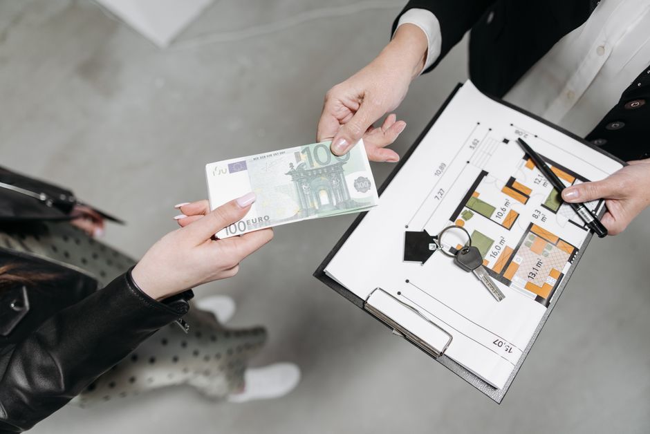 Close-up of a real estate transaction with euro bill, keys, and floor plan.