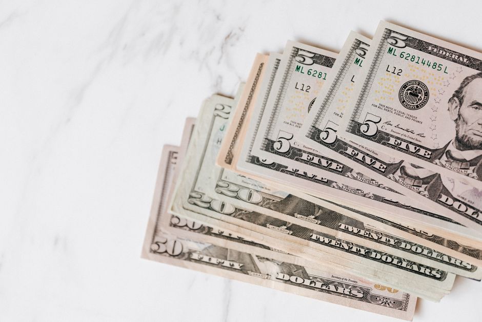 Top view of stack of US dollar banknotes in different denominations on marble table