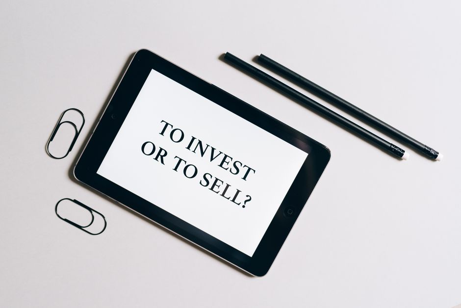 Flat lay of tablet with investment decision text, surrounded by stationery on a white table.